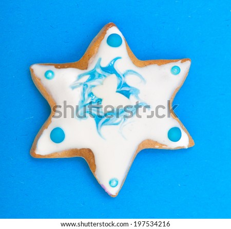 Homemade gingerbread cake star with icing and blue decoration on blue. Christmas and holiday handmade concept.