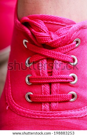 Closeup of casual vibrant pink sneakers plimsolls shoes boots on female feet. Sport fashion.