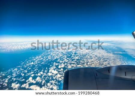 Blue sky and engine. View from window of airplane flying in clouds. Skyscape cloudscape. Bird\'s eye.