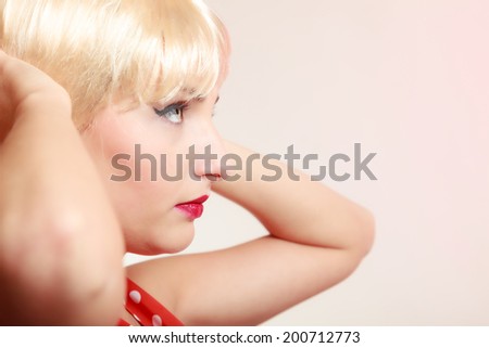 Vintage pinup style. Portrait of beautiful stylized young woman. Face of attractive girl in blond wig and with retro makeup. Disguise. Studio shot.