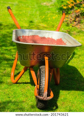 Gardening. Garden metal wheelbarrow with soil sand in the yard. Outdoor.