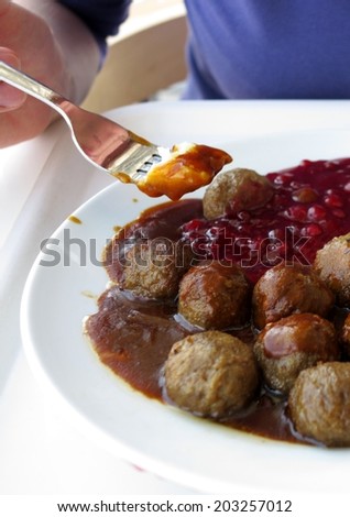 Food being eaten. Swedish meatballs potatoes cranberry on dish. A traditional scandinavian culinary.