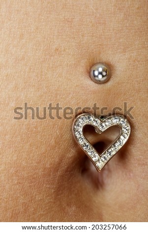 woman\'s belly with a piercing in the navel