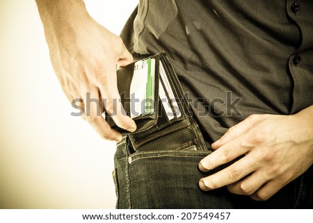 Closeup of male hands. Man taking the wallet out on his pocket. Pay and risk of theft. Isolated on white. Studio shot. Sepia tone.