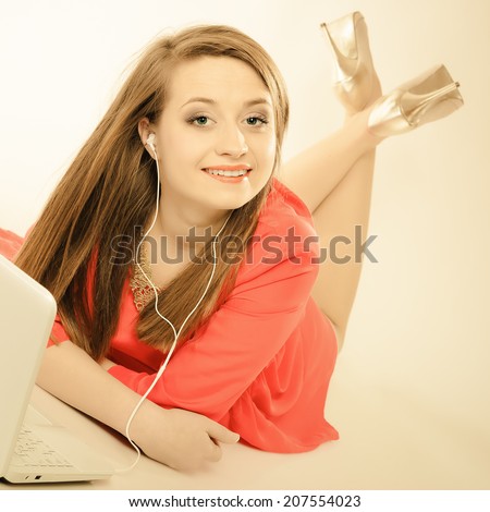 Leisure free time, music, online and internet concept - happy teenage girl with earphones and laptop computer