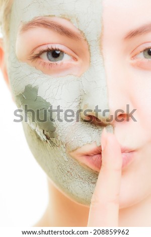 Skin care. Woman in clay mud mask on face with finger on lips isolated on white. Girl taking care of dry complexion. Secret of beauty.