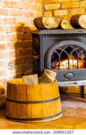 Winter at home. Closeup of fireplace with orange fire flame and firewood in the barrel interior. Heating.