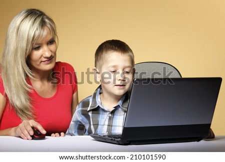 Education and technology. mother with son together looking on the laptop computer orange background