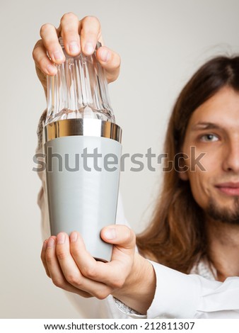 Young stylish man bartender with shaker making alcohol cocktail drink studio shot on gray