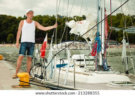Travel tourism vacation and people concept. Fashion portrait of handsome man on pier against yachts in port