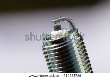 Auto service. New car spark plug as spare part of auto transportation on gray background.