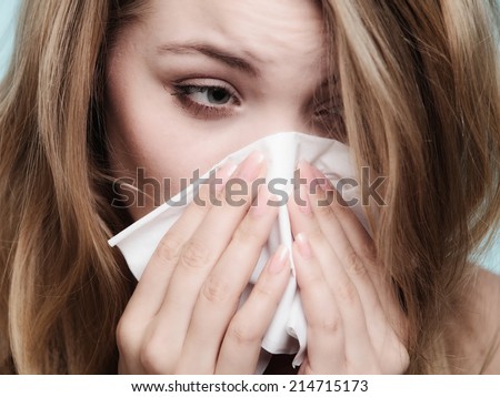Flu cold or allergy symptom. Sick woman girl sneezing in tissue on blue. Health care.