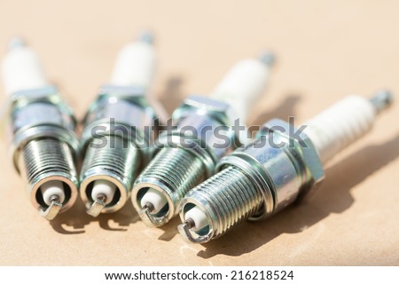 Auto service. Set of new car spark plugs as spare part of auto transportation on brown.