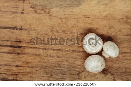 Vegetarian food. Fresh white mushrooms champigonons on wooden kitchen table as background.