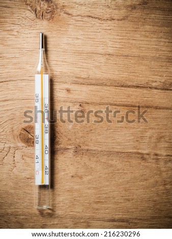 Medical background. Closeup of mercury thermometer on wooden background. Fever.