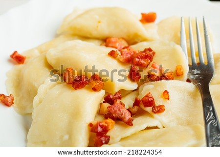 Closeup of dumplings sprinkled with pork scratchings with fork as food background. Traditional polish (Poland) cuisine.