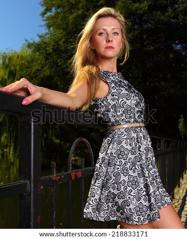 Fashionable young woman in summer flowery dress outdoor relaxing in park