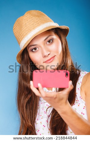 Technology internet and happy people concept - teen girl taking self picture selfie with smartphone camera, woman using cell phone on blue