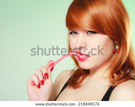 Sexy young woman holding candy. Redhair cute girl with sweet jelly on green.