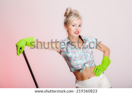 Sexy girl retro style with mop, woman housewife cleaner in domestic role. Traditional sharing household chores.  Pin up housework.  Pink background