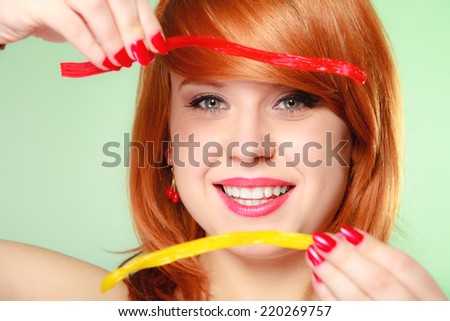 Sexy young woman holding candy. Redhair cute funny girl framing her face with sweet jelly on green