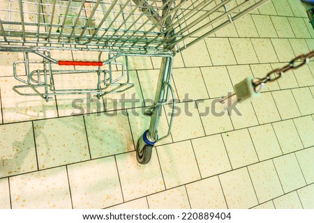 Closeup of empty metal shopping trolley cart on tiled floor in grocery store supermarket.