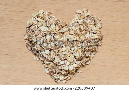 Dieting healthcare concept. Oat cereal heart shaped on wooden surface. Healthy food for lowering cholesterol, protect heart.