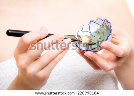 Skin care. Closeup of cosmetic. Woman with brush applying clay mask on face. Girl taking care of dry compexion. Spa.