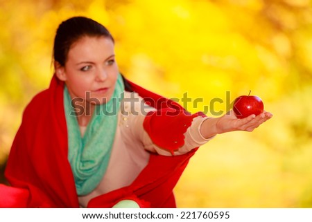 Fall lifestyle concept, harmony freedom. Casual young woman girl relaxing in autumnal park holding red apple. Golden colorful leaves background