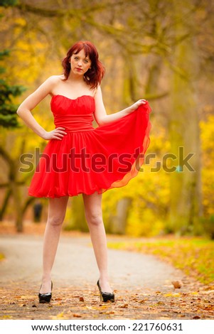 Full length fashionable elegant young woman in red dress outdoor relaxing walking in autumn park