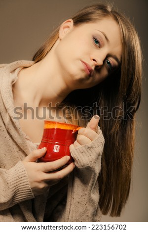 Hot beverage. Sleepy girl holding cup mug of drink tea or coffee. Woman in warm sweater warming herself