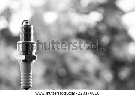 Auto service. New car spark plug as spare part of auto transportation on blurry gray background.