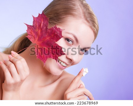 Skincare habits. Face of young woman with leaf as symbol of red capillary skin on violet. Girl taking care of her dry complexion applying moisturizing cream. Beauty treatment.