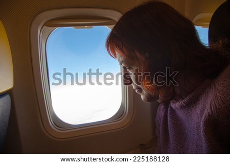 Travelling by air - woman is sitting in the airplane looking  through window