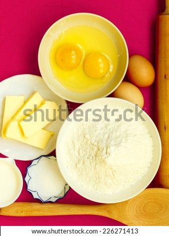Cooking concept. Preparation for baking, bake ingredients and kitchen tools to make a cake on pink nonstick silicone mat, top view