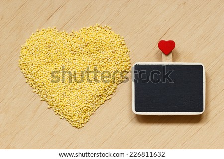 Dieting healthy food. Millet groats heart shaped and small blackboard board with space for text menu on wooden surface.