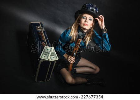 Criminal story bad girl steampunk retro woman with bag suitcase and gun studio shot grunge dark background