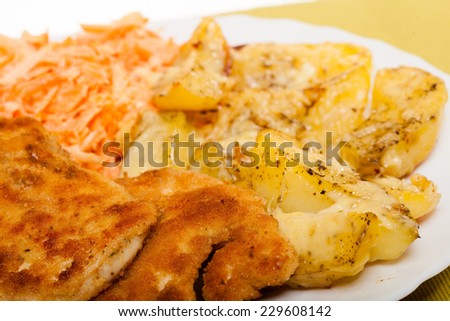 Dinner meal. Fried chicken roasted potatos with cheese and vegetables carrot salad on plate.