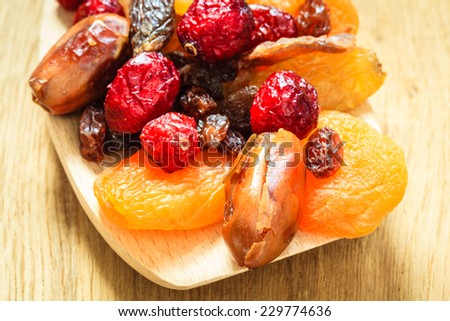 Healthy high fiber food, organic nutrition. Closeup different varieties mix of dried fruits on wooden spoon.