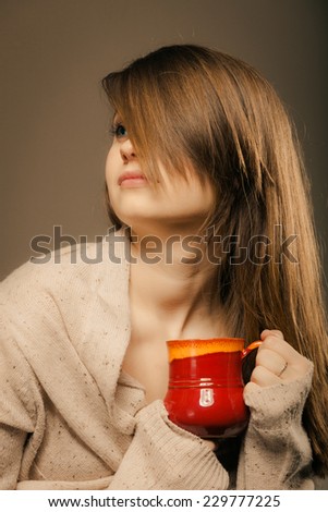 Hot beverage. Sleepy girl holding cup mug of drink tea or coffee. Woman in warm sweater warming herself