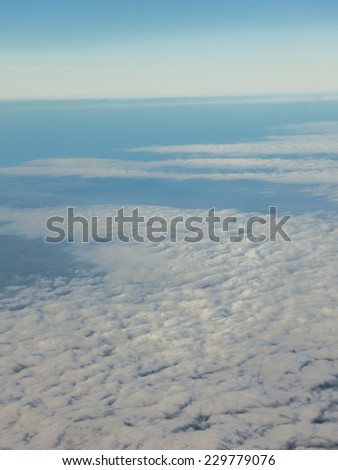 Blue sky. View from window of airplane flying in clouds. Skyscape cloudscape. Bird\'s eye.
