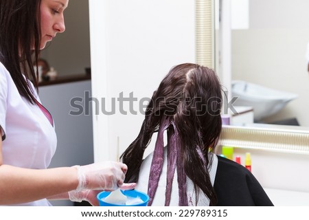 Professional female hairdresser applying color to female customer at design hair salon, woman having her hair dyed, Hair dye colouring in process