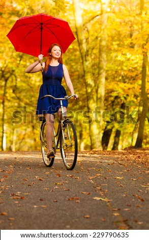 Happiness freedom and people concept. Redhaired beauty woman fashion girl on bicycle with red umbrella in autumnal park, having fun outdoor