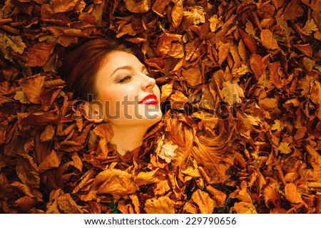 Ecology earth, eco friendly and love nature concept. Portrait young redhaired woman cover in autumn orange leaves.
