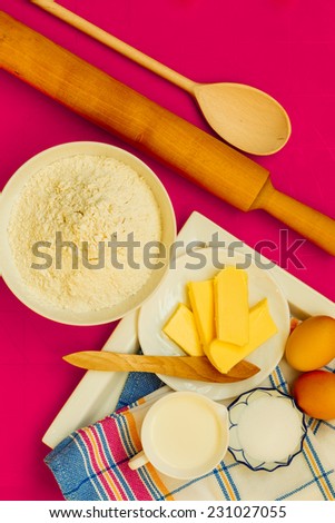 Cooking concept. Preparation for baking, bake ingredients and kitchen tools to make a cake on pink nonstick silicone mat, top view