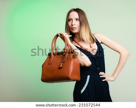 Elegant outfit. Stylish woman fashionable girl with brown leather handbag bag on green. Fashion and female beauty.