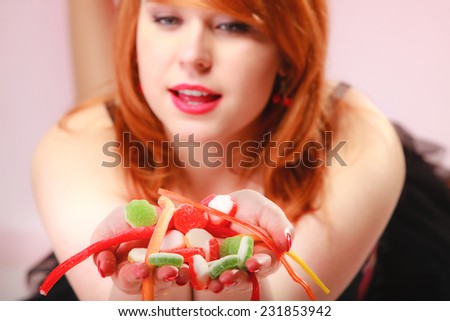 Sexy young woman holding candy. Redhair cute funny girl with sweet jelly on pink