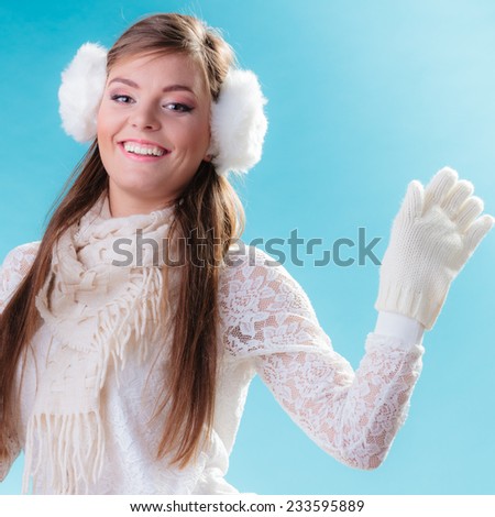 Winter fashion ear protection. Portrait positive teen girl in warm clothes. Happy woman in white earmuffs on blue