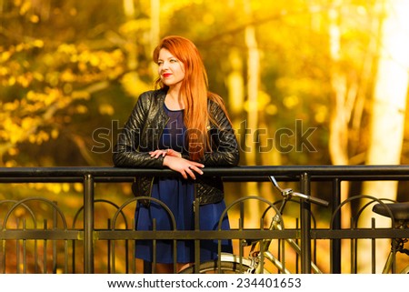 Fall active lifestyle concept,. Beauty young redhaired woman fashion girl relaxing in autumn park with bicycle, outdoor