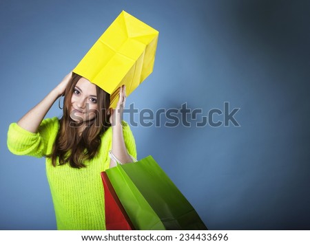 Funny crazy woman bright vivid colour sweater with paper shopping bag on head blue background. Sales and discounts concept.